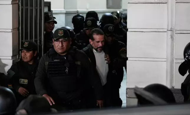 Suspended governor of Santa Cruz Luis Fernando Camacho is escorted by police out of court after a hearing on his arrest over charges of sedition and terrorism, in La Paz, Bolivia, Tuesday, Aug. 26, 2025. (AP Photo/Juan Karita)