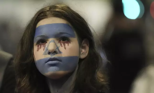 A woman with her face painted in the colors of the Israeli flag takes part in a protest demanding the end of the war, the immediate release of hostages held by Hamas in the Gaza Strip, and against Prime Minister Benjamin Netanyahu's government in Tel Aviv, Saturday, Aug. 16, 2025. (AP Photo/Mahmoud Illean)