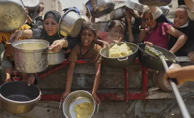 Palestinians struggle to get donated food at a community kitchen in Gaza City, northern Gaza Strip, Saturday, Aug. 16, 2025. (AP Photo/Jehad Alshrafi)