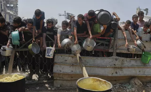 Palestinians struggle to get donated food at a community kitchen in Gaza City, northern Gaza Strip, Saturday, Aug. 16, 2025. (AP Photo/Jehad Alshrafi)