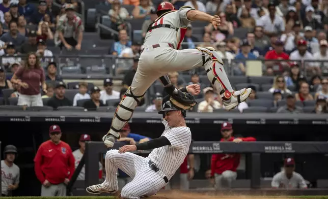 New York Yankees baseball player Cody Bellinger is tagged out at home plate by Philadelphia Phillies catcher J.T. Realmuto, top, in the third inning, in New York, July 27, 2025. (AP Photo/Angelina Katsanis)