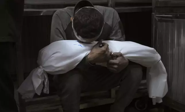Hossam Azzam holds the body of his son Amir who was killed in an Israeli military airstrike on Gaza, at Shifa Hospital in Gaza City, July 15, 2025. (AP Photo/Jehad Alshrafi)