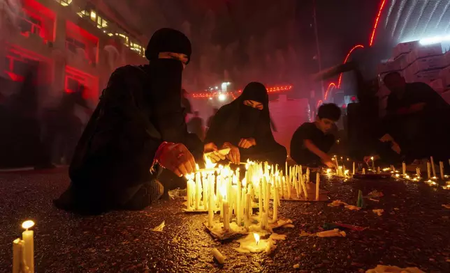 Shiite pilgrims light candles outside the holy shrine of Imam Hussein during a Muharram procession on Ashoura commemorating the martyrdom of Imam Hussein, the grandson of the Prophet Muhammad, in Karbala, Iraq, July 6, 2025. (AP Photo/Anmar Khalil)