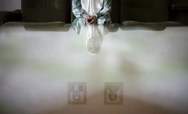Fadila Efendic, 74, reflected on a table, sits in her living room under pictures of her son and husband, victims of the Srebrenica genocide, in the village of Potocari near Srebrenica, Bosnia, June 28, 2025. Efendic lost a total of 22 members of her family to the genocide. (AP Photo/Armin Durgut)