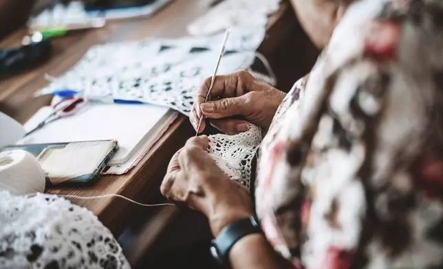 A woman makes traditional lace from cotton yarn in the village of Koniakow, in Poland's Beskid Mountains, Sunday, Aug. 17, 2025. (AP Photo/Daniel Franek)