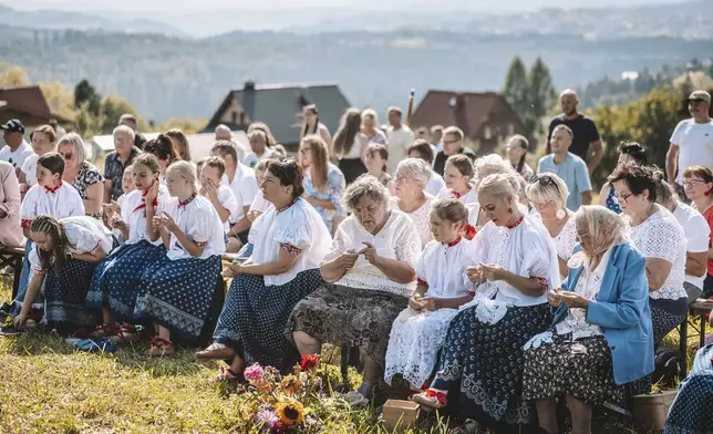 Women practice "hekla", the traditional art of hand-crocheted lace making, on a valley slope in the village of Koniakow, Poland, Sunday, Aug. 17, 2025. (AP Photo/Daniel Franek)