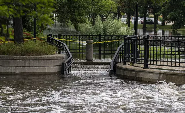 Water pours over steps on a riverwalk along the Fox River, Monday, Aug. 11, 2025, in Waukesha, Wis. (AP Photo/Andy Manis)