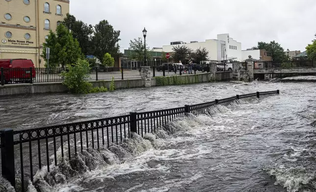 People watch along the Fox River Monday, Aug. 11, 2025, in Waukesha, Wis. (AP Photo/Andy Manis)
