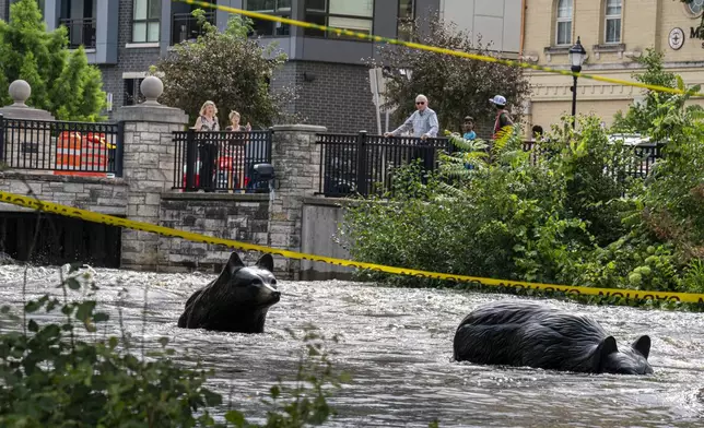 People watch along the Fox River Monday, Aug. 11, 2025, in Waukesha, Wis. (AP Photo/Andy Manis)