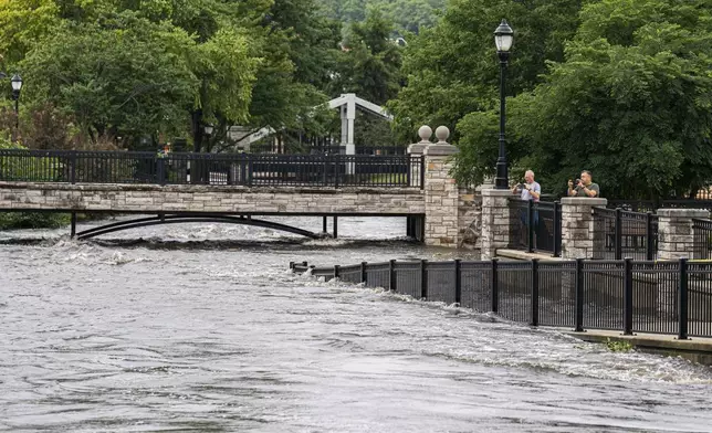 People watch along the Fox River Monday, Aug. 11, 2025, in Waukesha, Wis. (AP Photo/Andy Manis)