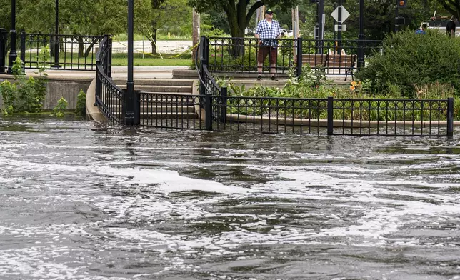People watch along the Fox River Monday, Aug. 11, 2025, in Waukesha, Wis. (AP Photo/Andy Manis)