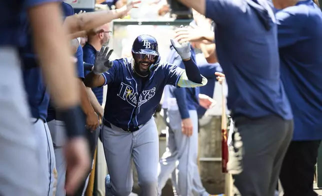 Tampa Bay Rays' Junior Caminero is greeted by teammates in the dugout after hitting a home run during the third inning of a baseball game against the Los Angeles Angels Wednesday, Aug. 6, 2025, in Anaheim, Calif. (AP Photo/William Liang)