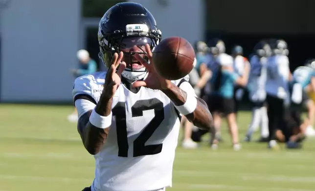 Jacksonville Jaguars wide receiver Travis Hunter (12) makes a reception in a defensive pass drill during practice at the team's NFL football training camp, Sunday, July 27, 2025, in Jacksonville, Fla. (AP Photo/John Raoux)