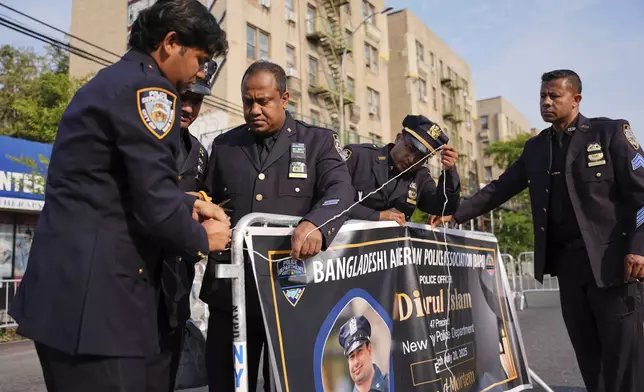 New York Police officers hang a banner for the funeral of officer Didarul Islam, Thursday, July 31, 2025, in New York. (AP Photo/Angelina Katsanis)