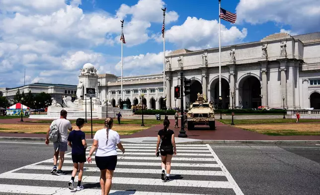 FILE - People walk to Union Station as District of Columbia National Guard soldiers stand outside their M-ATV, Aug. 16, 2025, in Washington. (AP Photo/Julia Demaree Nikhinson, File)