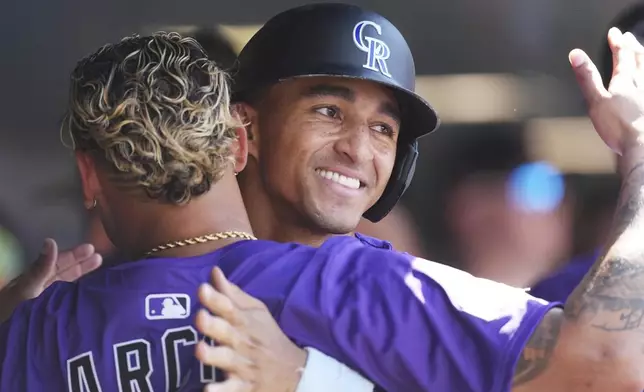Colorado Rockies' Orlando Arcia, front, congratulates Ryan Ritter after he scored on a single hit by Mickey Moniak off Arizona Diamondbacks relief pitcher Jake Woodford in the seventh inning of a baseball game Sunday, Aug. 17, 2025, in Denver. (AP Photo/David Zalubowski)