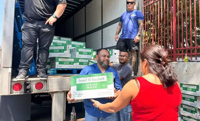 People, who were affected by a water main break that that led to reduced service to nearly 200,000 homes and businesses, pick up cases of bottled water at John F. Kennedy High School in Paterson, N.J., on Aug. 11, 2025. (AP Photo/Ted Shaffrey)