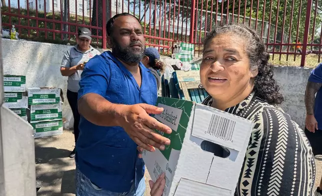 People, who were affected by a water main break that that led to reduced service to nearly 200,000 homes and businesses, pick up cases of bottled water at John F. Kennedy High School in Paterson, N.J., on Aug. 11, 2025. (AP Photo/Ted Shaffrey)