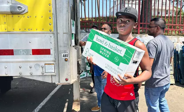 People, who were affected by a water main break that that led to reduced service to nearly 200,000 homes and businesses, pick up cases of bottled water at John F. Kennedy High School in Paterson, N.J., on Aug. 11, 2025. (AP Photo/Ted Shaffrey)