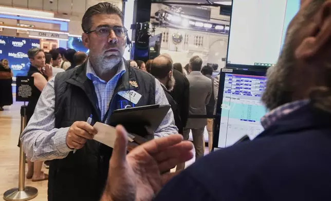 Trader Michael Capolino left, works on the floor of the New York Stock Exchange, Monday, Aug. 18, 2025. (AP Photo/Richard Drew)