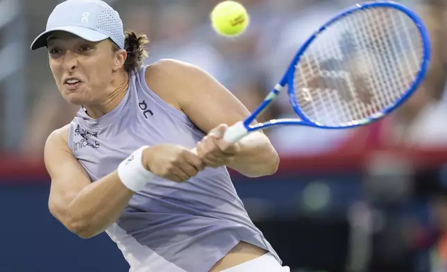 Iga Swiatek, of Poland, hits a return to Eva Lys, of Germany, during third-round match action at the National Bank Open women's tennis tournament in Montreal, Friday, Aug. 1, 2025. (Christinne Muschi/The Canadian Press via AP)