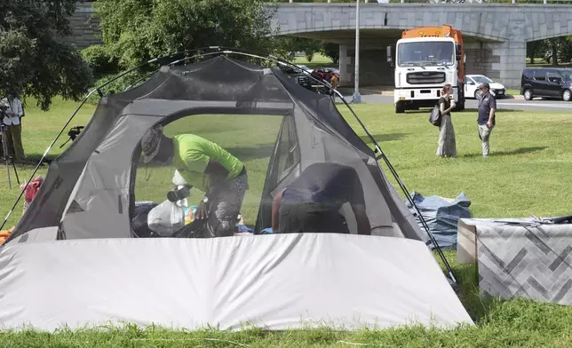 Trash trucks wait as the homeless empty their belongs from their tents, Thursday, Aug. 14, 2025, in Washington. (AP Photo/Jacquelyn Martin)
