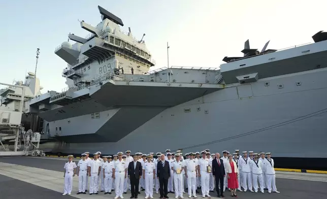 Guests and crews of the Royal Navy aircraft carrier HMS Prince of Wales pose for a group photo during its port call in Tokyo Thursday, Aug. 28, 2025. (AP Photo/Eugene Hoshiko)
