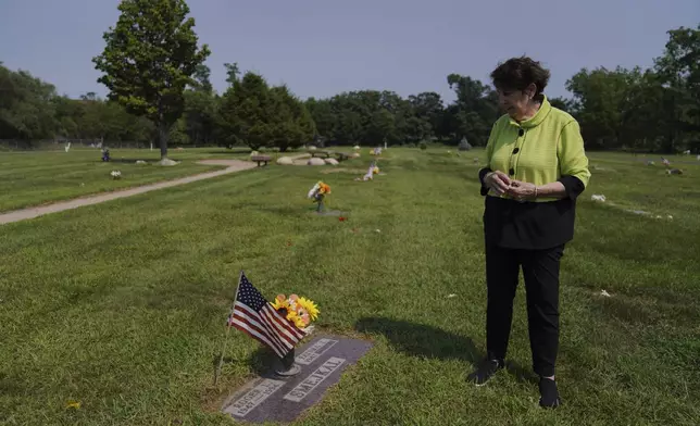 Fatima Igram Smejkal, whose family immigrated from present-day Lebanon to the United States in the early 1900s, stands beside her husband's grave in the Muslim National Cemetery, established in the 1940s, in Cedar Rapids, Iowa, on Friday, Aug. 8, 2025. (AP Photo/Jessie Wardarski)
