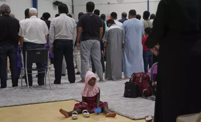 A young girl watches as men and women pray at the Islamic Center of Cedar Rapids on Friday, Aug. 8, 2025, in Cedar Rapids, Iowa. (AP Photo/Jessie Wardarski)