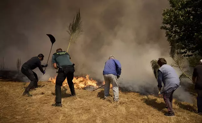 Residents battle a fire advancing toward Rebordondo village, near Ourense, in northwestern Spain, on Monday, Aug. 18, 2025. (AP Photo/Pablo Garcia)