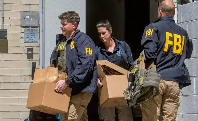 FBI agents carry boxes from former National Security Advisor John Bolton's office in Washington, Friday, Aug. 22, 2025. (AP Photo/Rod Lamkey, Jr.)