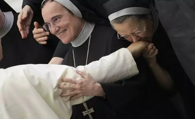 A nun kisses the hand of Pope Leo XIV during his weekly general audience, at The Vatican, Wednesday, Aug.20, 2025. (AP Photo/Gregorio Borgia)