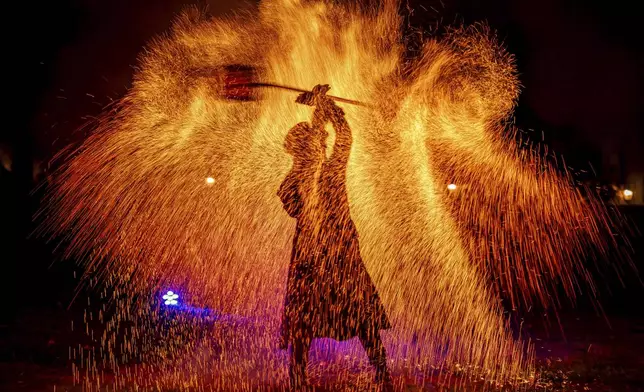 A man performs a pyrotechnic show at the Palace of Versailles before the fireworks display in Versailles, outside Paris, Friday, Aug. 15, 2025. (AP Photo/Aurelien Morissard)