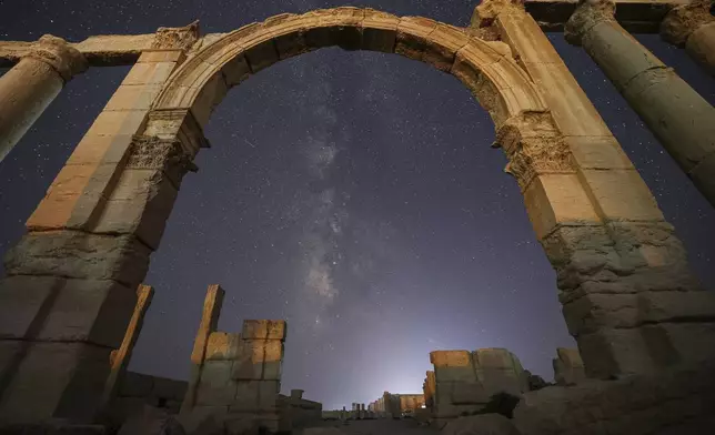 The entrance to the Roman Theater's precinct, part of the ruins of the ancient city of Palmyra, is seen under a star-studded sky in Syria, late Wednesday, Aug. 27, 2025. (AP Photo/Ghaith Alsayed)