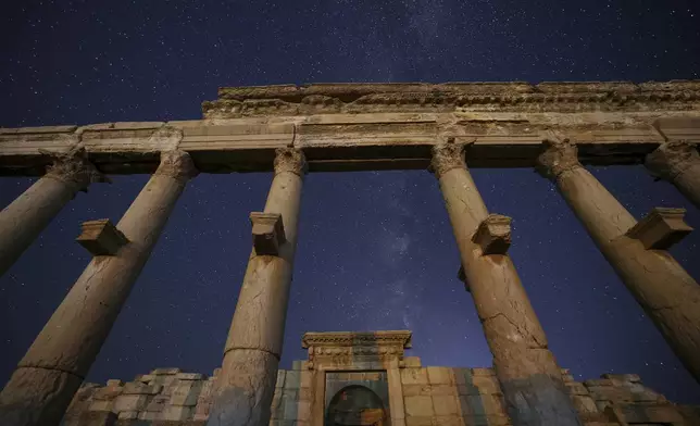 Columns of the Long Street, foreground, and the rear gate of the Roman Theater in the ruins of the ancient city of Palmyra are seen under a star-studded sky in Syria, late Wednesday, Aug. 27, 2025. (AP Photo/Ghaith Alsayed)