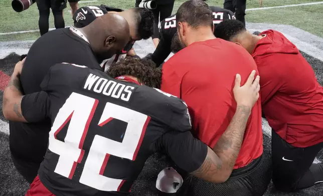 Atlanta Falcons players pray after their NFL preseason football game was suspended after Detroit Lions safety Morice Norris was injured Friday, Aug. 8, 2025, in Atlanta. (AP Photo/Brynn Anderson)