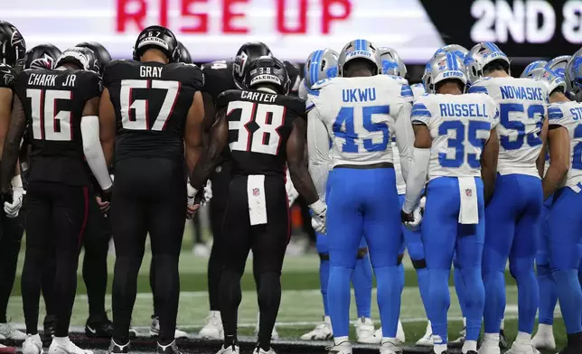 Atlanta Falcons and Detroit Lions players stand on the field hand in hand together after Detroit Lions safety Morice Norris was injured during the second half of an NFL preseason football game Friday, Aug. 8, 2025, in Atlanta. (AP Photo/Brynn Anderson)