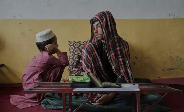 A religious studies teacher instructs a boy in Quran recitation at the Abdullah Ibn-Masoud religious school on the outskirts of Kabul, Afghanistan, Monday, May 26, 2025. (AP Photo/Ebrahim Noroozi)