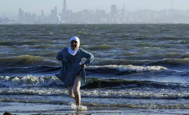 A girl plays on the shore at Albany Beach as the San Francisco skyline is seen in the background Wednesday, Aug. 6, 2025, in Albany, Calif. (AP Photo/Godofredo A. Vásquez)