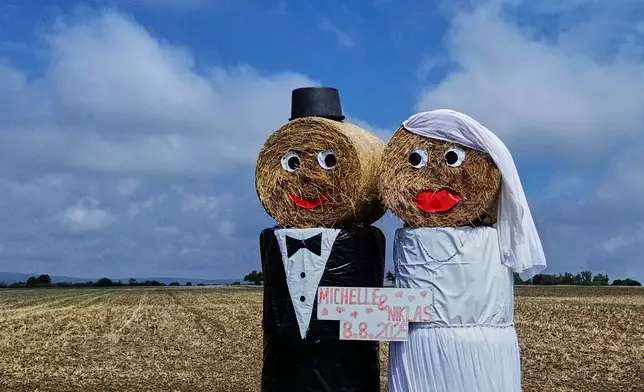 Straw bales are decorated as a wedding couple to point out an upcoming wedding in the outskirts of Frankfurt, Germany, Monday, Aug. 4, 2025. (AP Photo/Michael Probst)