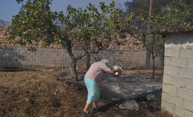 Stamatina, 86, tries to extinguish a wildfire in Keratea, at the outskirts of Athens, Friday, Aug. 8, 2025. (AP Photo/Thanasis Stavrakis)