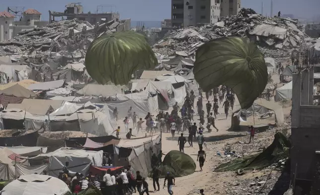 Palestinians rush to collect humanitarian aid airdropped by parachutes into Gaza City, northern Gaza Strip, Thursday, Aug. 7, 2025. (AP Photo/Jehad Alshrafi)