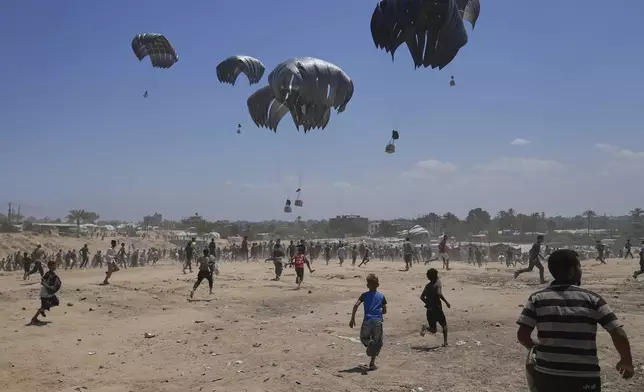 Palestinians rush to collect humanitarian aid airdropped by parachutes into Zawaida in the central Gaza Strip, Monday, Aug. 4, 2025. (AP Photo/Abdel Kareem Hana)