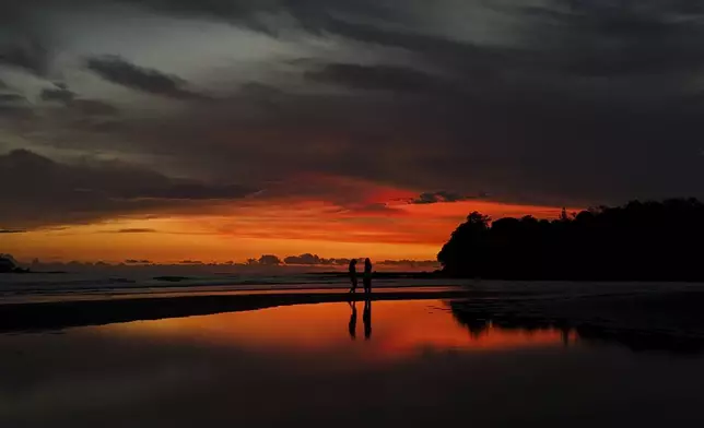 People walk along the shore in Santa Catalina, Panama, Wednesday, Aug. 6, 2025. (AP Photo/Matias Delacroix)