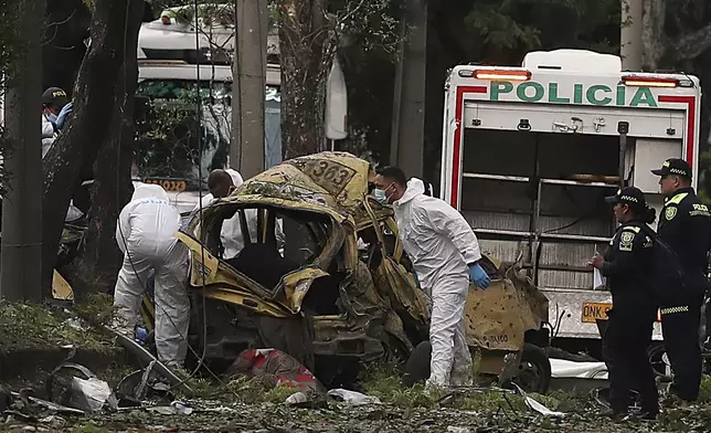 Forensics inspect the site of a bomb explosion outside an Air Force base in Cali, Colombia, Thursday, Aug. 21, 2025. (AP Photo/Santiago Saldarriaga)
