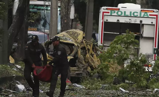 Police remove wreckage from the site of a bomb explosion outside an Air Force base in Cali, Colombia, Thursday, Aug. 21, 2025. (AP Photo/Santiago Saldarriaga)