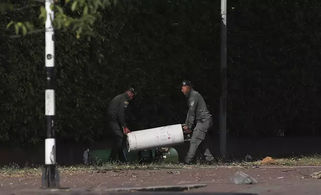 Security forces inspect the site of a bomb explosion outside an Air Force base in Cali, Colombia, Thursday, Aug. 21, 2025. (AP Photo/Santiago Saldarriaga)