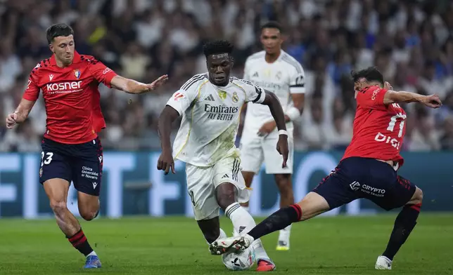 Real Madrid's Aurelien Tchouameni in action between Osasuna's Abel Bretones, left, and Ante Budimir during the La Liga soccer match between Real Madrid and Osasuna in Madrid, Spain, Tuesday, Aug. 19, 2025. (AP Photo/Manu Fernandez)
