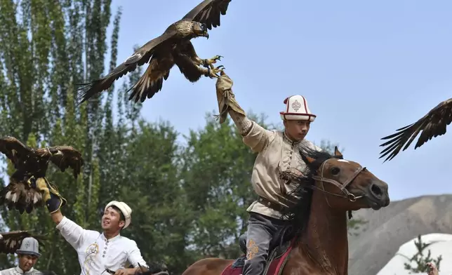 Kyrgyz hunters with golden eagles get ready to compete during the Traditional Eagle Hunting Salbuurun Festival on the southern shore of Issyk-Kul lake, 213 km (132 miles) southeast of Bishkek, Kyrgyzstan, on Saturday, Aug. 2, 2025. (AP Photo/Vladimir Voronin)