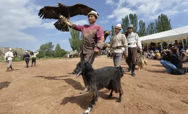 Kyrgyz hunters with their golden eagles and hunting dogs Taigan also known as Kyrgyz Taighany during the Traditional Eagle Hunting Salbuurun Festival on the southern shore of Issyk-Kul lake, 213 km (132 miles) southeast of Bishkek, Kyrgyzstan, on Saturday, Aug. 2, 2025. (AP Photo/Vladimir Voronin)